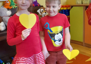 Dzieci trzymają żółte serca.
