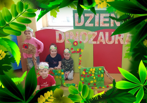 Grupka dzieci z sylwetami dinozaurów.