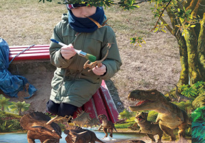 Dzieci szukają dinozaurów ukrytych w piaskownicy - w ramce z dinozaurami