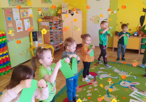 Dzieci robią wiosenny wietrzyk, dmuchają w zielone kartki.