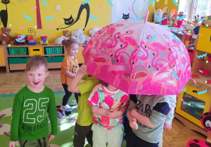 Dzieci ukrywają się pod parasolem przed wiosennym deszczem.