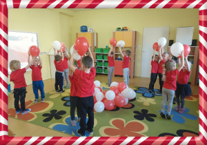 Dzieci trzymają białe i czerwone balony.