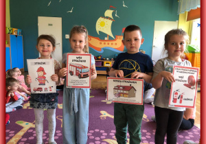 Dzieci prezentują karty ilustrujące wyposażenie strażaka