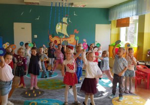 Na zdjęciu grupa dzieci.Dzieci trzymają kolorowe koła. Podnoszą rączkę do góry.