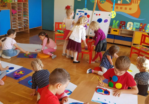 Dzieci malują farbami na białych kartonach .