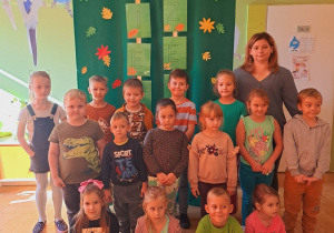 Grupa dzieci pozuje do zdjęcia z p. Agnieszką. W tle napis-Dzień Drzewa.