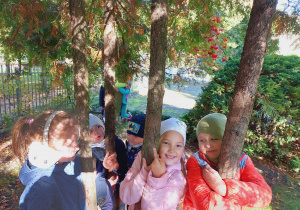 Dzieci przytulają się do drzew w ogrodzie przedszkolnym.