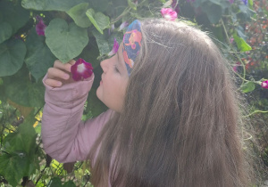 Dziewczynka wącha kwiaty.