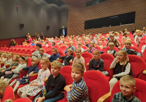 Dzieci siedzą na sali w teatrze i oczekują na przedstawienie.
