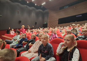 Dzieci siedzą na sali w teatrze i oczekują na przedstawienie.