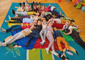 Dzieci leżą na kolorowej chuście animacyjnej.