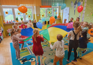 Dzieci podrzucają balony na chuście animacyjnej.