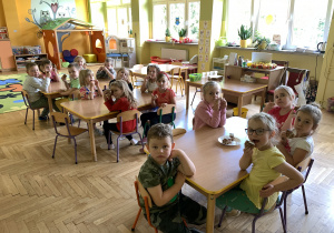 Dzieci przy stolikach z na stołach stoi ciasto