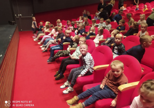 Dzieci siedzą w sali czekając na spektakl.