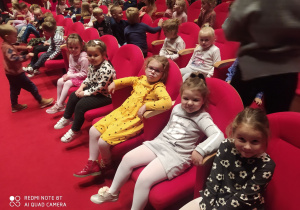Dzieci siedzą w sali czekając na spektakl.