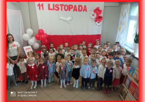 Dzieci na tle biało - czerwonej dekoracji 11 Listopada.