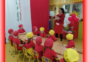 Dzieci siedzą przy stolikach, słuchają krótkiej historyjki na temat Włoch.