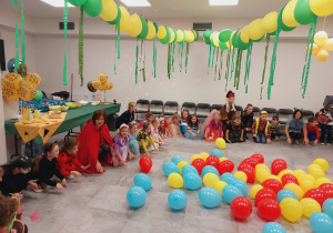 Przebrane dzieci bawią się na udekorowanej balonami sali