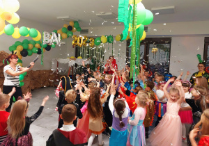 Przebrane dzieci bawią się na udekorowanej balonami sali