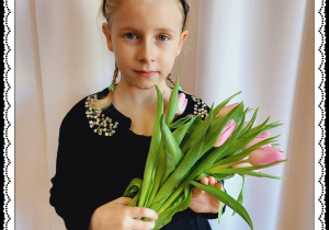 Dziewczynka trzyma różowe tulipany.