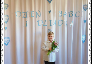Chłopiec trzyma różowe tulipany. W tle napis Dzień Babci i Dziadka.