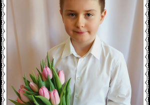 Chłopiec trzyma różowe tulipany.