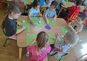 Dzieci przy stolikach wykonują pączki z masy solnej