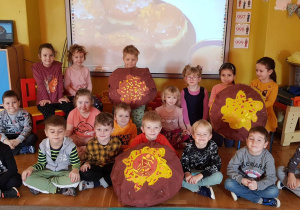 Dzieci z grupy 3 prezentują swoje duże pączki wykonane z papieru i pomalowane farbami.