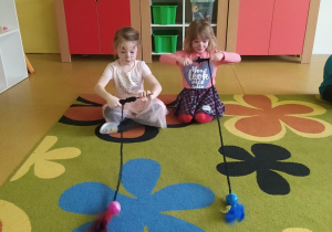 Dwie dziewczynki bawią się w zabawę, kto szybciej zwinie kocią zabawkę