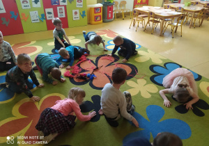 Dzieci na dywanie chodzą jak kotki i bawią się piłeczkami