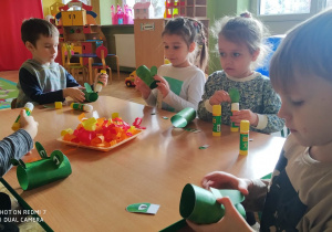 Dzieci wykonują prace plastyczną przy stolikach