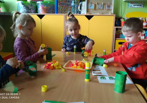 Dzieci wykonują pracę plastyczną przy stolikach