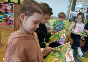 Dzieci oglądają ilustracje z dinozaurami