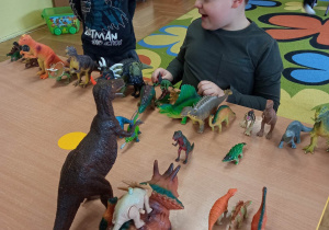 Dzieci patrzą na zabawki-dinozaury