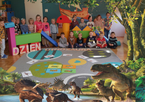 Zdjęcie w ramce z dinozaurami. Na zdjęciu grupa dzieci .