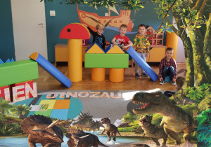 Zdjęcie w ramce z dinozaurami. Dzieci ułożyły dinozaura z piankowych klocków.