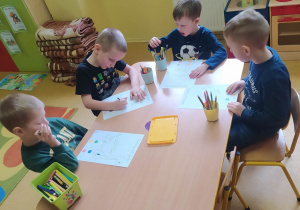 Dzieci rozwiązują zadania przy stolikach
