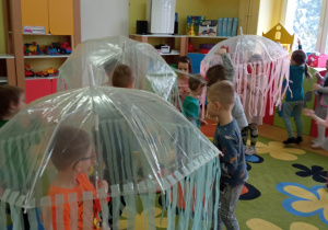 Dzieci chowaja sie pod parasolami w czasie przerwy w muzyce.
