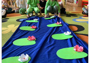 Dzieci przebrane za żabki skaczą po liliach