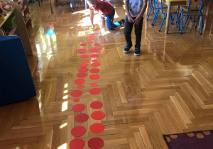 Dzieci układają na podłodze wzory z kolorowych kółek