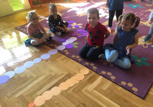 Dzieci układają na podłodze kwiatka z kolorowych kółek
