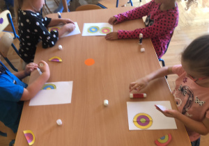 Dzieci naklejają na kartkę dwie połówki kolorowych kółek, które pasują do siebie.