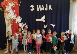 Dzieci z grupy 6, na tle dekoracji z okazji obchodów 3 Maja