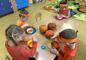 Dzieci nasypują barwiony na pomarańczowo ryż do słoiczków-lampioników