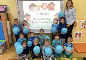 Dzieci z panią Olą ubrane na niebiesko i z niebieskimi balonami