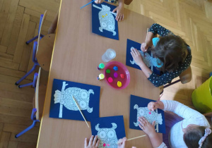 Dzieci wykonują pracę plastyczną, kolorowa sowa w kropki.