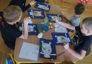 Dzieci wykonują pracę plastyczną, kolorowa sowa w kropki.