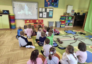 Dzieci oglądają film edukacyjny o tematyce drzew.