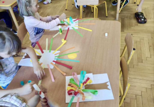 Dzieci wykonują pracę plastyczna kolorowe drzewo.