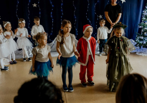 Występ dzieci - dziewczynki w złotych bluzkach i granatowych spódniczkach, Mikołaj i Choinka
